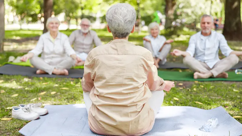 instructor leading meditation for group of elderly people