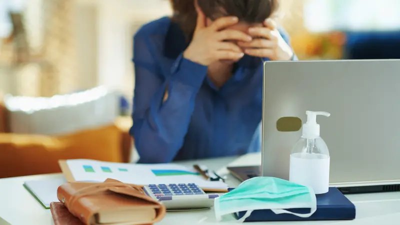 medical mask and hand disinfectant and stressed woman in background in temporary home office during the coronavirus epidemic