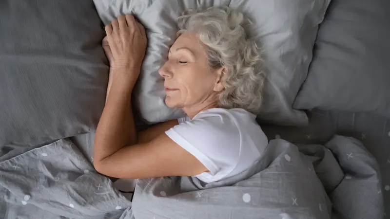 woman sleeping on soft pillow under blanket, enjoying sweet dreams at night