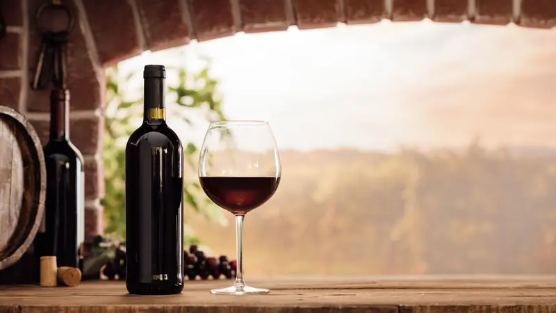 wineglass and bottles next to the window and panoramic view of vineyards at sunset wineglass and bottles next to the window and panoramic view of vineyards at sunset