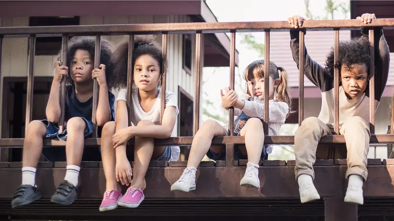 little children sitting behind the fence.