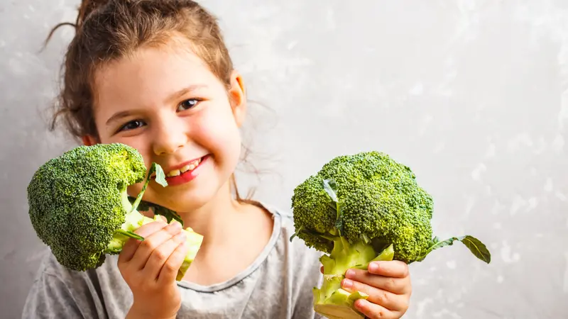 Little girl eating broccoli