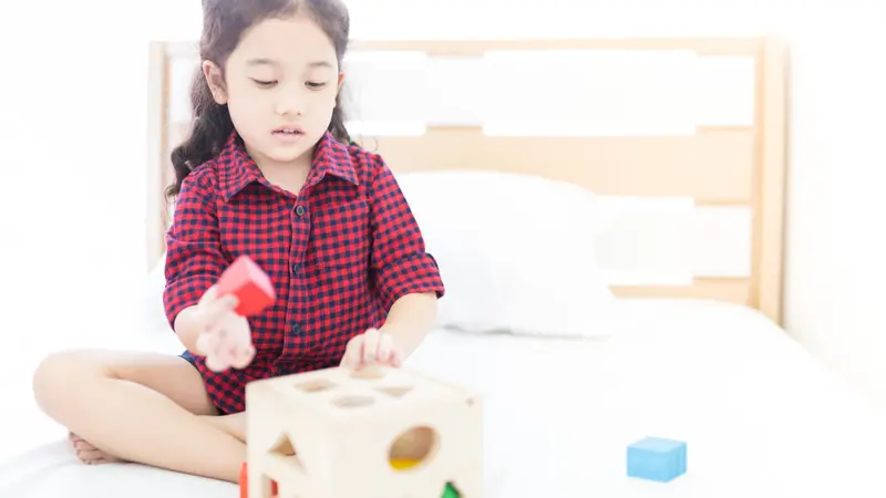  girl playing a wood puzzle toy on her bed, education training, children development toy