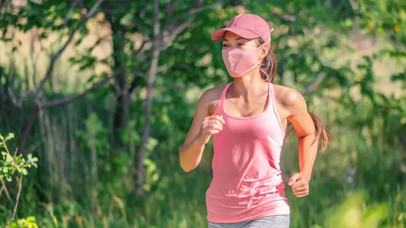 woman running outside with face covering while exercising jogging on run sport workout in summer