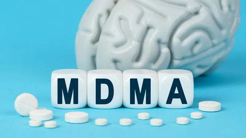 Medicine and health. Cubes lie on the table among the pills and imitation of the brain. The text on the dice - MDMA