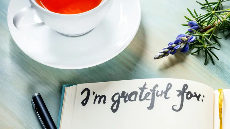 Gratitude journal with a flower and a cup of tea, with the handwritten phrase I am grateful for