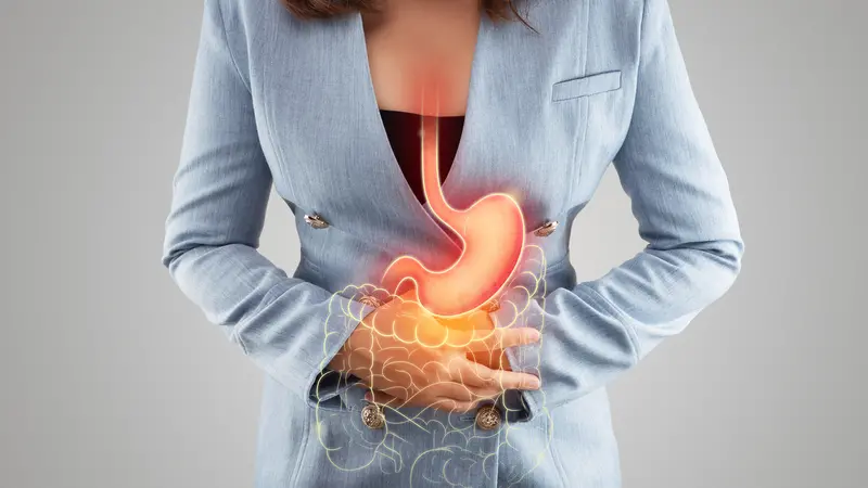 The illustration of stomach and large intestine is on the woman's body against gray background. The illustration of stomach and large intestine is on the woman's body against gray background.