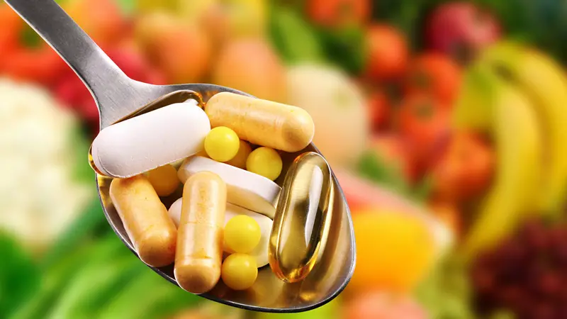 Spoon with dietary supplements on fruits background Spoon with dietary supplements on fruits background