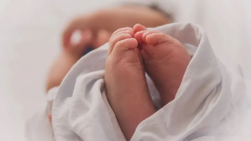 Monthly Gathering -Birth Stories image of babies feet sticking out of swaddling- Photo by Luma Pimentel on Unsplash