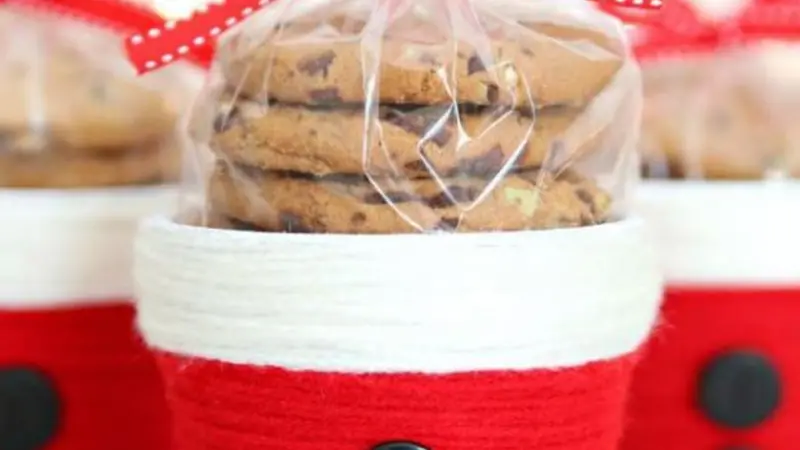 red cups with white trim and buttons decorated like Santa's coat filled with wrapped cookies and topped with a bow