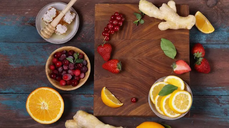 collection of foods, fruit, berries, ginger and honey on a cutting board