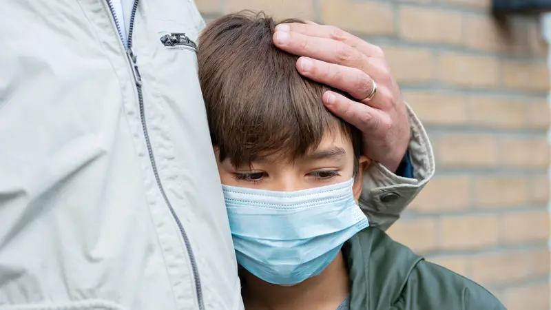 A father comforting a son in a medical mask, depression, being sad and lonely because of Covid-19