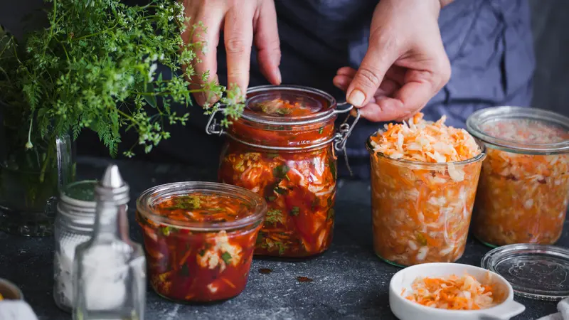Fermented preserved vegetables food concept. Cabbage kimchi and sauerkraut sour cabbage glass jars, over rustic blue table Fermented preserved vegetables food concept. Cabbage kimchi and sauerkraut sour cabbage glass jars, over rustic blue table