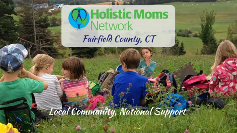 Image of children having a snack in a field with Holistic Moms Network logo and Fairfield County CT inset in a white box at center top