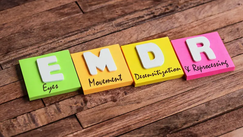 Colorful square papers with wooden white letters for the English acronym word, EMDR