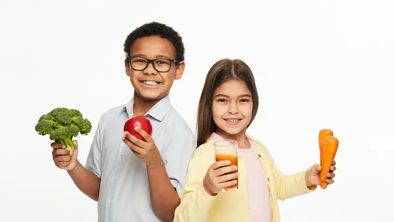 Multi-ethnic group of children with healthy vegetables, fruits, and carrot juice