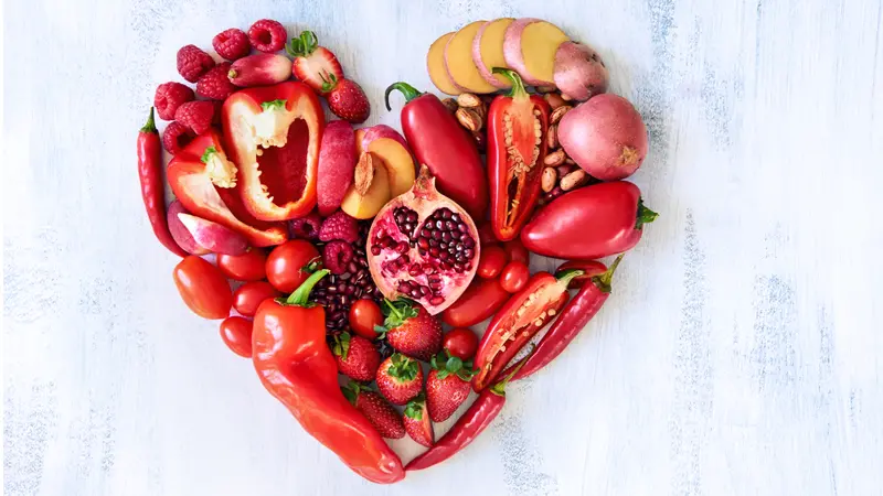 Collection of fresh red vegetables and fruits arranged in a heart shape on white rustic background strawberry raspberry pomegranate peppers capsicum chilli potato beans Collection of fresh red vegetables and fruits arranged in a heart shape on white rustic background strawberry raspberry pomegranate peppers capsicum chilli potato beans