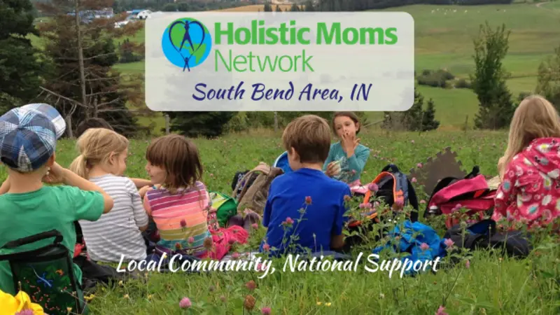 Image of children having a snack in a field with Holistic Moms Network logo and South Bend IN inset in a white box at center top