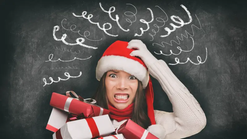 Christmas stress, woman in Santa hat stressed out, drawings of headache spirals on black blackboard Christmas stress, woman in Santa hat stressed out, drawings of headache spirals on black blackboard