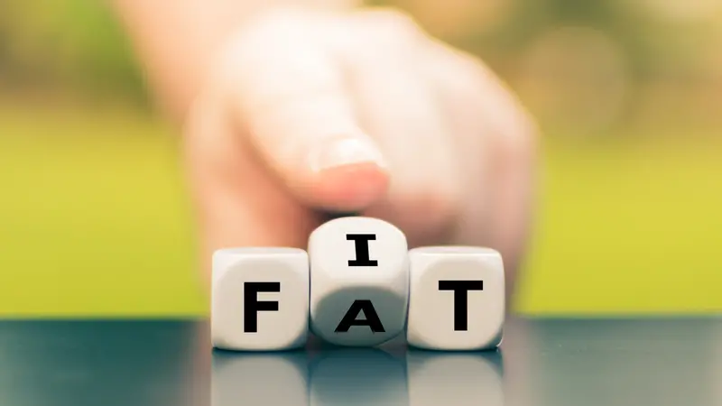 Hand turns dice and changes the word "fat" to "fit"