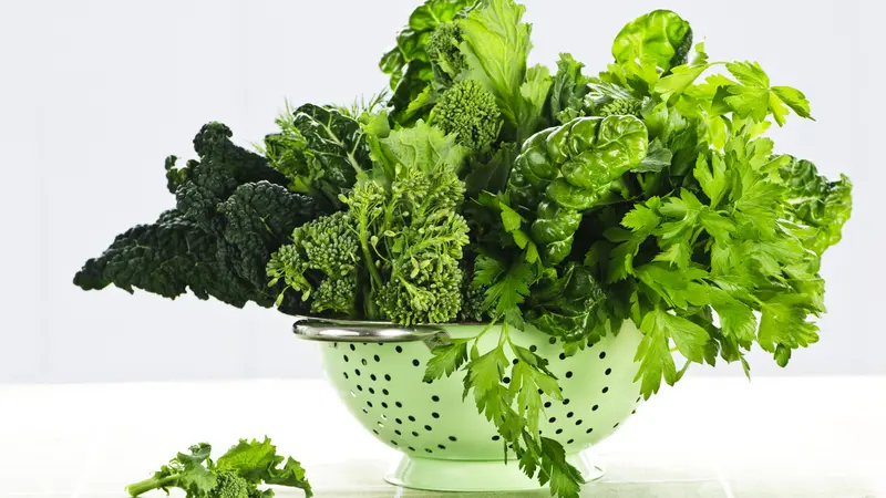 Dark green leafy fresh vegetables in metal colander Dark green leafy fresh vegetables in metal colander