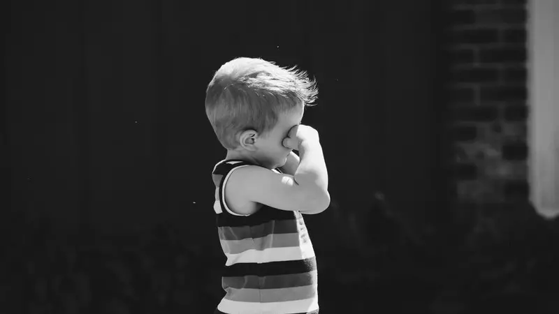 Seasonal Allergies black and white photo of a small child with striped tank top rubbing his eyes
