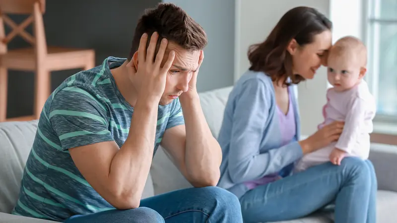 Happy mother with her baby and young father suffering from postnatal depression at home