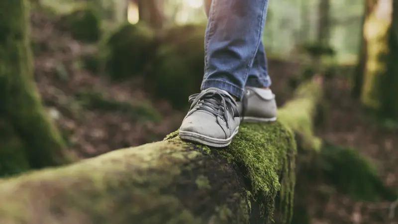 Woman walking on a log in the forest and balancing