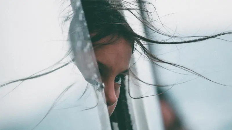 child peeking out a window, hair blowing through the opening