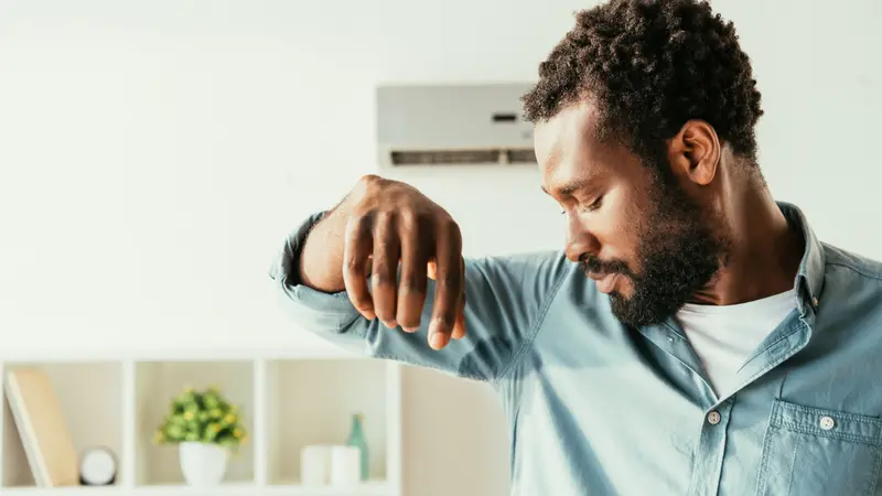 African American man looking at sweaty shirt 