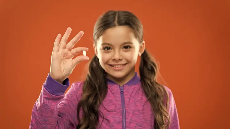 Girl hold probiotic tablet.