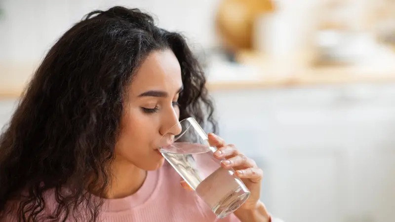 Woman Drinking Water From Glass In Kitchen