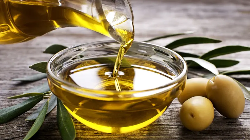 Bottle pouring virgin olive oil in a bowl close up Bottle pouring virgin olive oil in a bowl close up