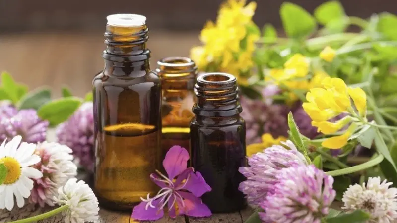Flower Essences 3 amber essential oil bottles sitting on a table surrounded by flowers.