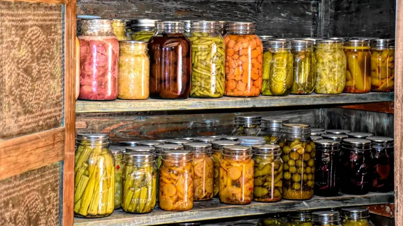 rows of canned foods stored in a pantry on shelving