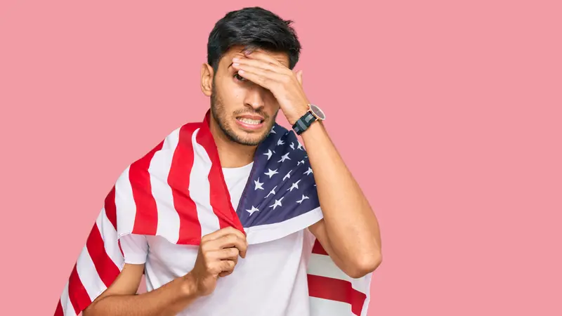 Young handsome man holding united states flag stressed