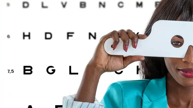 African-American woman taking an eyesight test examination at an optician clinic with Eye Chart Illustrations on background