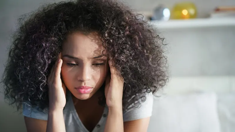 Depressed Hispanic girl at home, looking away with sad expression.