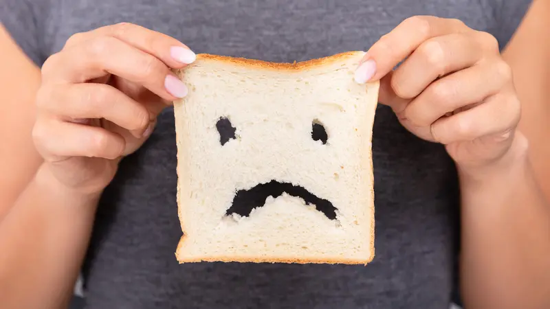Mid-section Of A Woman Hands Holding Sliced Bread With Unhappy Face Cut Out