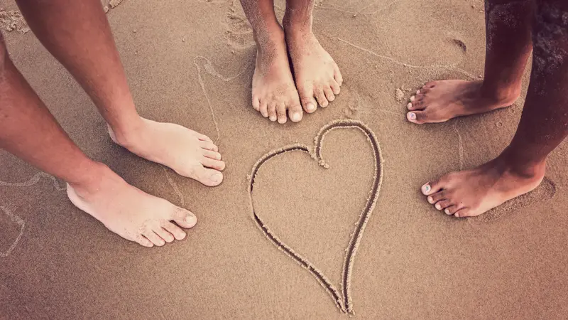 Racially diverse children's feet at the beach with a heart drawn Racially diverse children's feet at the beach with a heart drawn