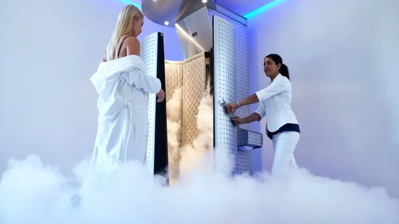Female taking cryotherapy treatment with beautician standing at the capsule door. Female taking cryotherapy treatment with beautician standing at the capsule door.