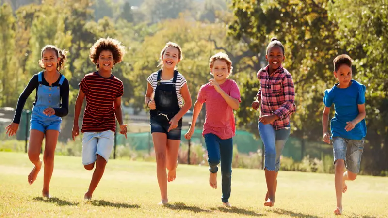 Six pre-teen friends running in a park, front view, close up