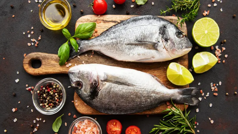 Fresh fish and ingredients for cooking on a table.