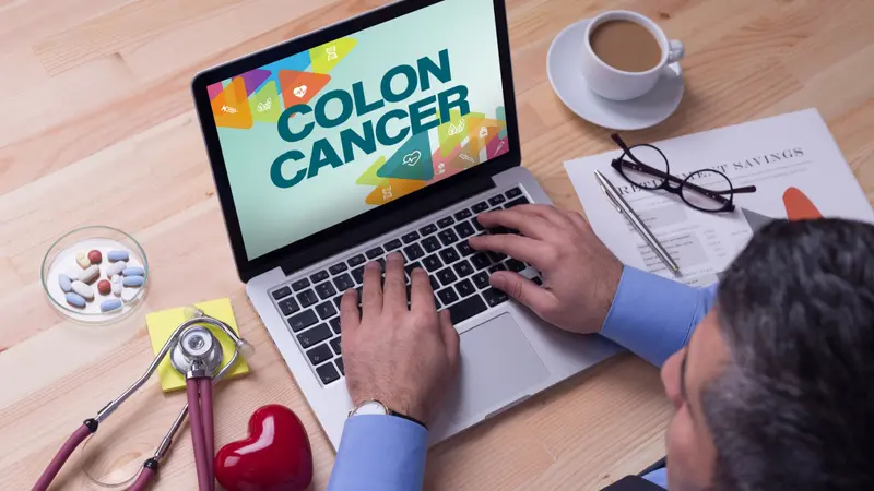 Doctor working on a laptop and COLON CANCER on his screen