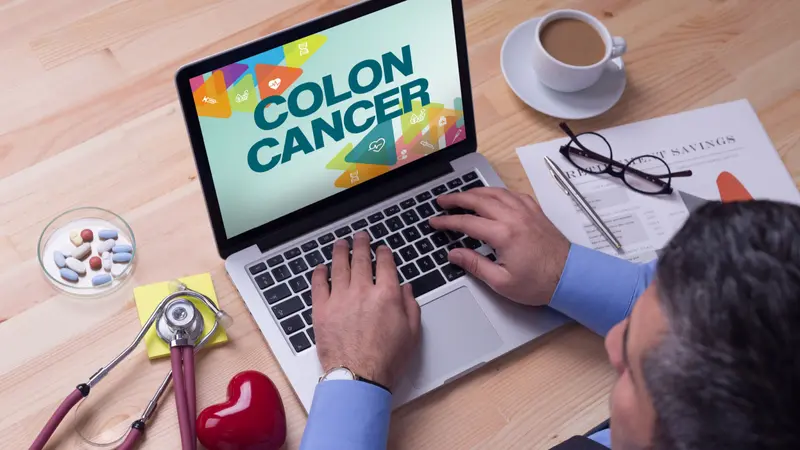 Doctor working on a laptop and COLON CANCER on his screen Doctor working on a laptop and COLON CANCER on his screen