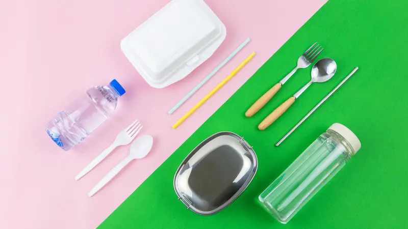 Flat lay photo comparison between disposable foam container, plastic cutlery, plastic straw, plastic bottle and reusable lunch box, spoon, fork straw and water bottle on two colours, pink and green. Flat lay photo comparison between disposable foam container, plastic cutlery, plastic straw, plastic bottle and reusable lunch box, spoon, fork straw and water bottle on two colours, pink and green.