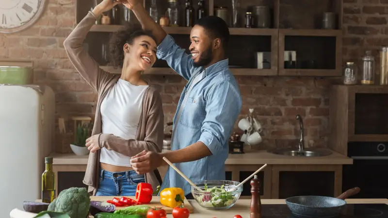 Happy romantic couple dancing in kitchen while cooking together Happy romantic couple dancing in kitchen while cooking together