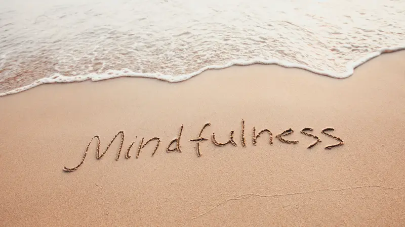Mindfulness concept, text written on the sand of beach