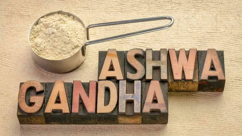 Scoop of ashwagandha root powder with a text in vintage letterpress wood type