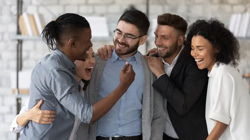 Standing and hugging smiling team laughing looking at each other. Standing and hugging smiling team laughing looking at each other.